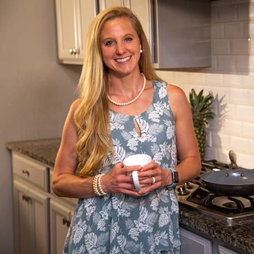 Kelsey Shepperd in a kitchen smiling and holding a coffee mug