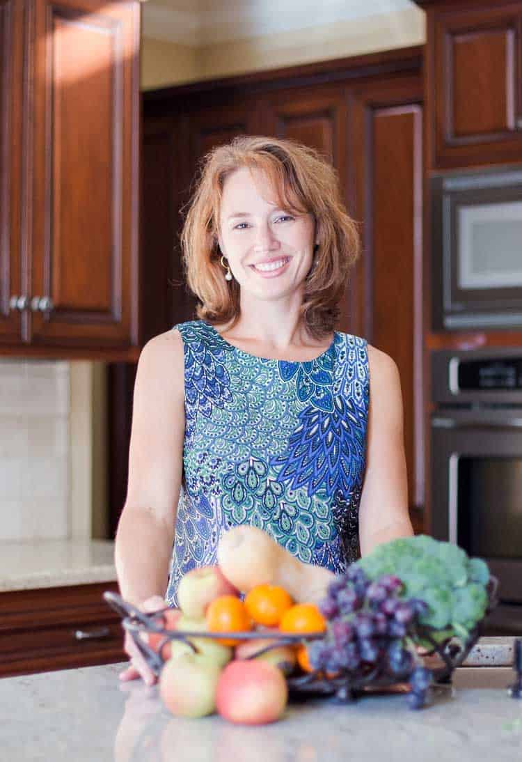 Karen Harrison in her kitchen smiling with healthy foods on counter